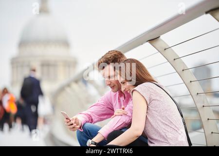 Couple looking at smartphone on city bridge Stock Photo