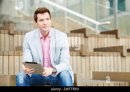 Man sitting on steps with a tablet Stock Photo