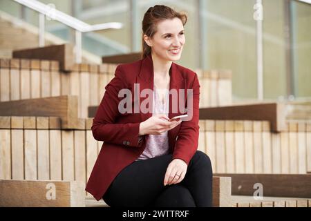 Woman sitting on steps holding a phone Stock Photo