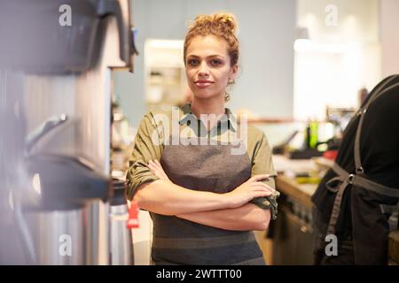 Confident woman in apron standing in a kitchen Stock Photo