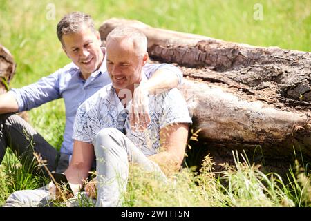 Two men smiling and sitting together outdoors Stock Photo