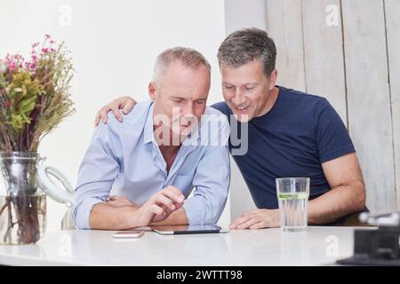 Two men using a tablet at a table. Stock Photo