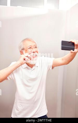 Elderly man taking a selfie with a phone. Stock Photo