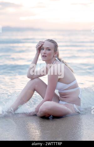 Woman sitting on the beach at sunset Stock Photo