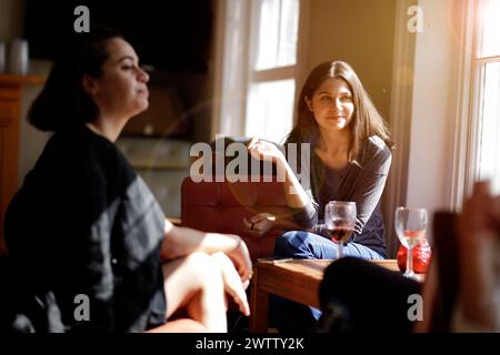 Friends enjoying a conversation in a cozy room with sunlight Stock Photo