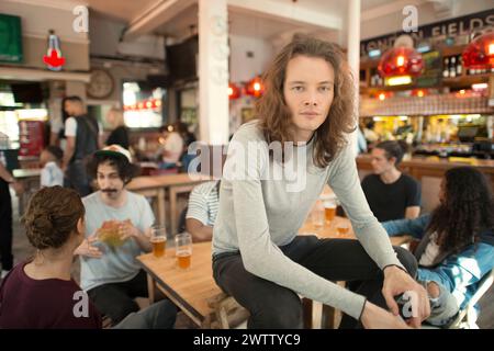 Young man sitting in a busy bar Stock Photo