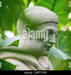 Closeup of the statue of St. Francis of Assisi surrounded by palm leaves at the Como Park Zoo and Marjorie McNeely Conservatory in St. Paul, Minnesota. Stock Photo