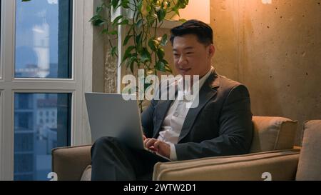 Korean Chinese businessman ethnic Asian man working with laptop at modern office skyscraper male employer business worker CEO manager distant work in Stock Photo