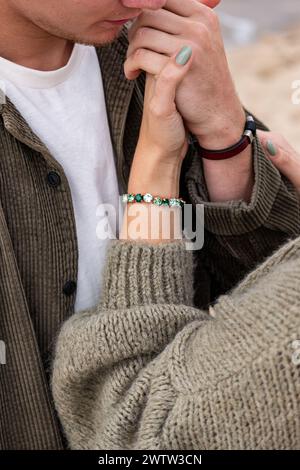 Close-up of a womans hand on a mans face, showcasing a turquoise bracelet. It evokes a sense of tender connection, and love in young age.. High qualit Stock Photo