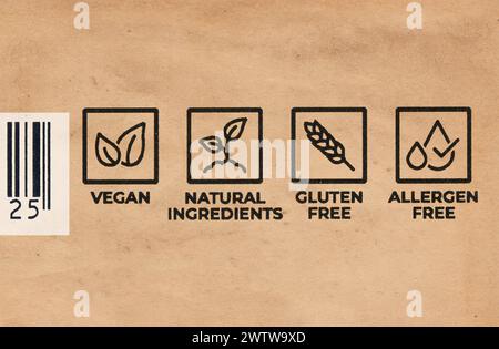 Labels on a food package saying Vegan, Natural Ingredients Gluten Free Allergen Free with part of a barcode. Close up image on brown paper. Copenhagen Stock Photo