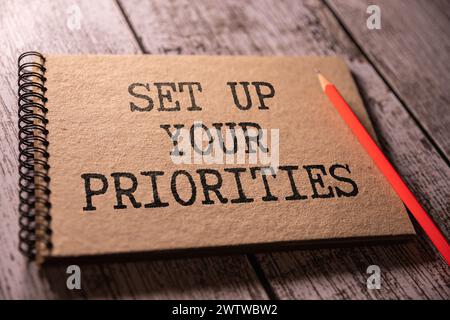 SET UP YOUR PRIORITIES text on a clipboard on wooden background. Stock Photo