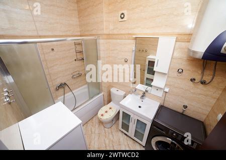 Shower cabin in the bath next to the toilet, washbasin, washing machine, wardrobe and boiler in the bathroom. Top view Stock Photo