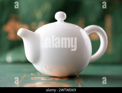 White porcelain Chinese teapot on a green background close up Stock Photo