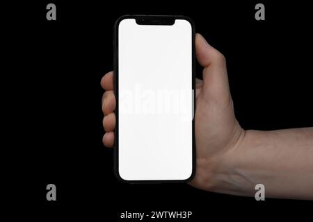 A male hand holding a blank phone screen on a black background Stock Photo