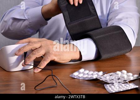 The picture shows a man who, using a device for measuring blood pressure, measures his pressure. Stock Photo