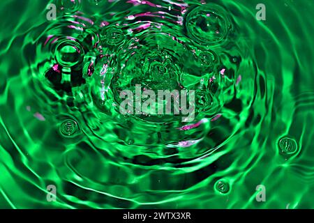A snapshot of the green surface of the water and the waves created by the falling drops. Stock Photo