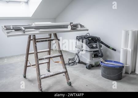 Home renovation - empty room with pasting table for cutting wallpaper and tools Stock Photo