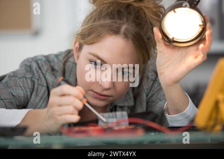 young female electronic engineer soldering computer motherboard in laboratory Stock Photo