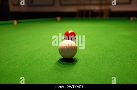 Red and white snooker balls on the green baize of a snooker table; a cue ball and an object ball. Stock Photo