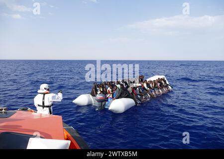 African migrants packed onto a flimsy boat being rescued off the coast of Libya by a humanitarian ship in the Mediterranean on 12th July, 2016. Stock Photo