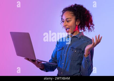 Excited woman with arms open using laptop Stock Photo
