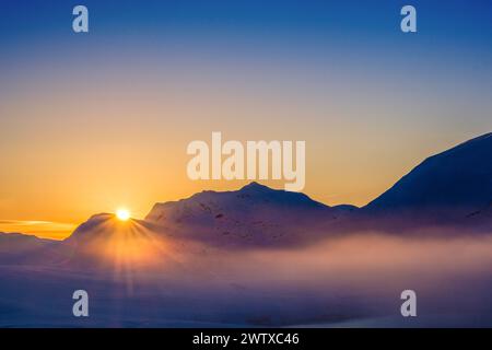 sun setting behind the mountains of the Jotunheim / Jotunheimen, Norway Stock Photo