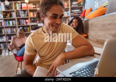 Portrait of young male student study in the library using laptop for researching online. Stock Photo