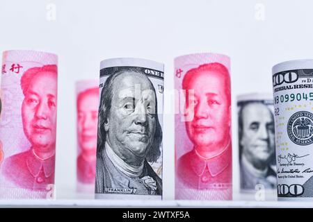Rolls 100 US dollar and 100 Chinese yuan renminbi banknotes background. Stock Photo