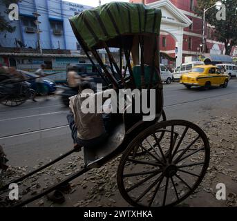 A sat rickshaw driver waiting for customers by a road in Kolkata, West Bengal, India Stock Photo