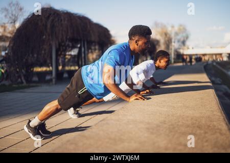 Two friends are exercising in the city. They are doing push-ups. Stock Photo