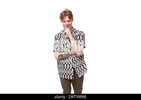young focused caucasian man with red hair with a tattoo dressed in a summer black and white shirt on a background with copy space Stock Photo