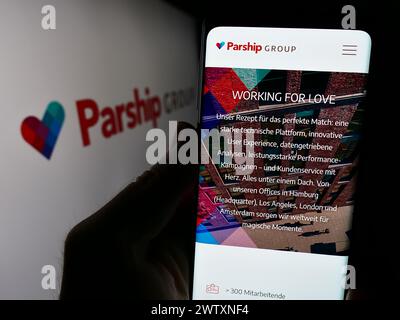 Person holding smartphone with webpage of German online dating company ParshipMeet Holding GmbH with logo. Focus on center of phone display. Stock Photo