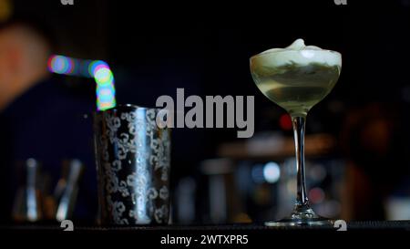 A professional bartender preparing an alcoholic cocktail with cream topping. Media. Making a beverage at the bar or disco club. Stock Photo