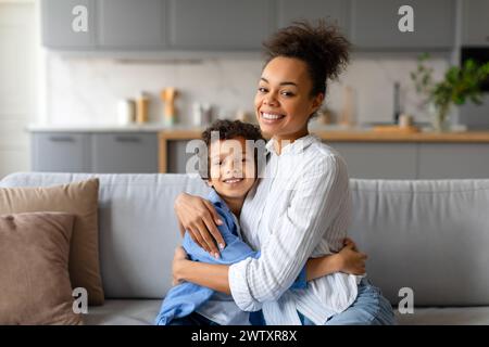 Joyful mother and son sitting on couch Stock Photo