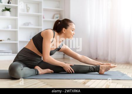 Beautiful young asian female making stretching exercises at home Stock Photo