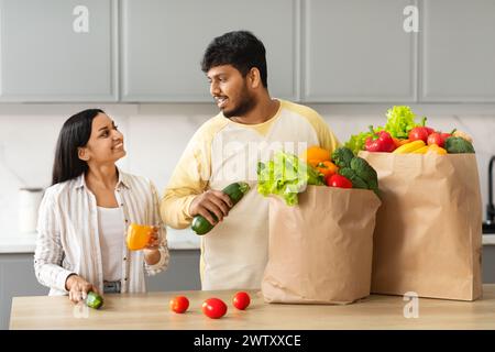 Happy Indian Couple Unpacking Bag With Groceries In Kitchen Stock Photo