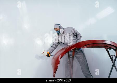 Authentic shot. Car painter repairman painter in chamber painting automobile car bumper in car service. Stock Photo