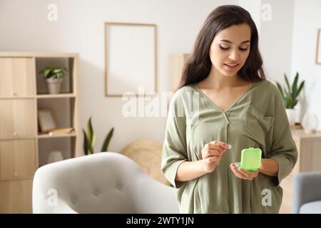 Young woman taking pills from pillbox at home Stock Photo