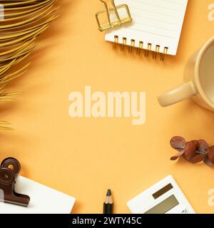 Workspace concept. Note, memo pad, clip, pencil, calculator, mug cup, plant on orange desk background. flat lay, top view, copy space Stock Photo