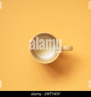 Ceramic cup of milk on orange table background. top view Stock Photo