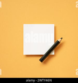White blank memo notepad and pencil on orange desk background. top view, copy space Stock Photo