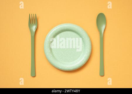 Empty green plate and cutlery on orange table background. flat lay, top view Stock Photo