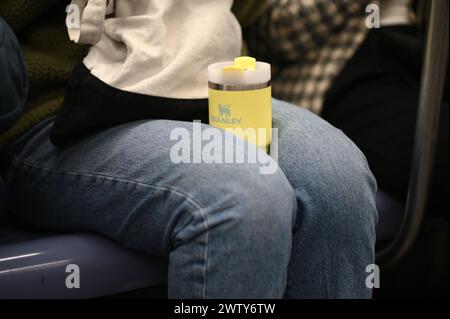 New York, USA. 15th Mar, 2024. A commuter holds a Stanley tumbler with her legs while riding a New York City subway, New York, NY, March 15, 2024. Due in part to social media driven popularity, Stanley tumblers, which come in a variety of sizes and colors, have become a very sought after product, causing a website crashes and rush-to-get at new product launch. (Photo by Anthony Behar/Sipa USA) Credit: Sipa USA/Alamy Live News Stock Photo