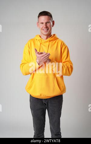 Young man clapping hands against gray background Stock Photo