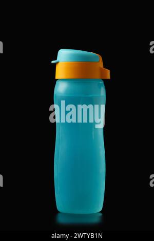 Reusable colorful eco-plastic bottle for water and other hot and cold drinks on a black background. Environment protection. Stock Photo