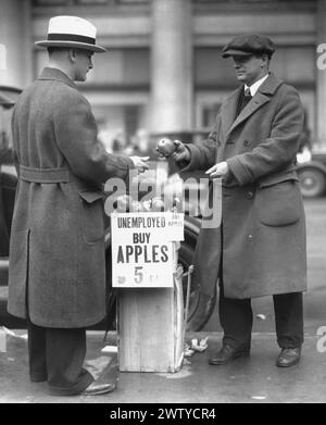 A smartly dressed unemployed man is pictured on the sidewalk selling apples during the depression Stock Photo