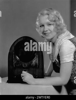 Actress Anita Page posing next to a tabletop radio with her hand on the dial. Stock Photo