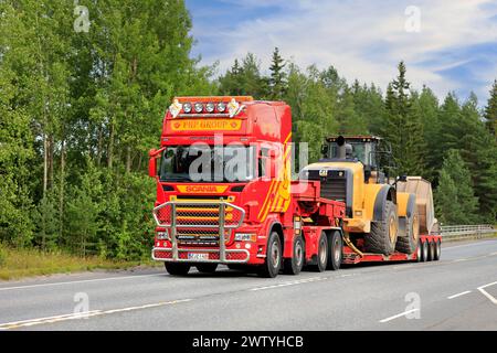 Customised Scania truck of PHP Group transports Cat 980K wheel loader on Nooteboom low loader trailer on Highway 2. Forssa, Finland. August 11, 2022. Stock Photo