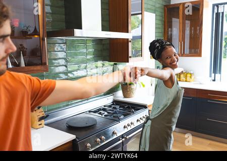 A diverse couple dancing and having fun in the kitchen at home Stock Photo