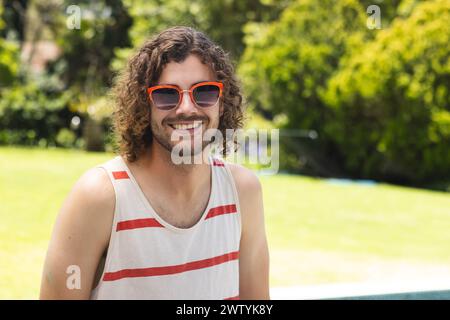 A young Caucasian man with curly hair smiles outdoors with copy space at home Stock Photo